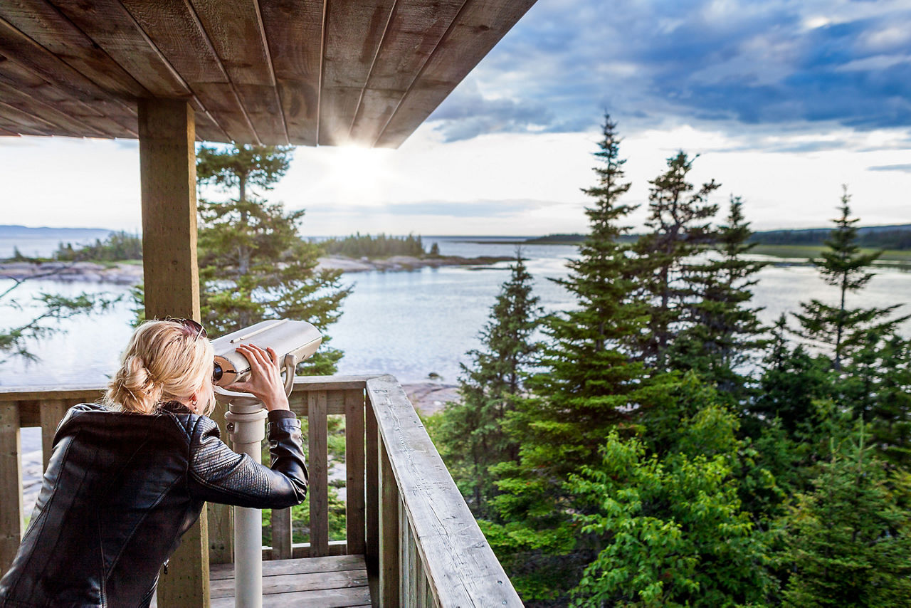 Young Woman Looking at the Amazing Nature Through a Binocular in a Observation Tower in Quebec, Canada.