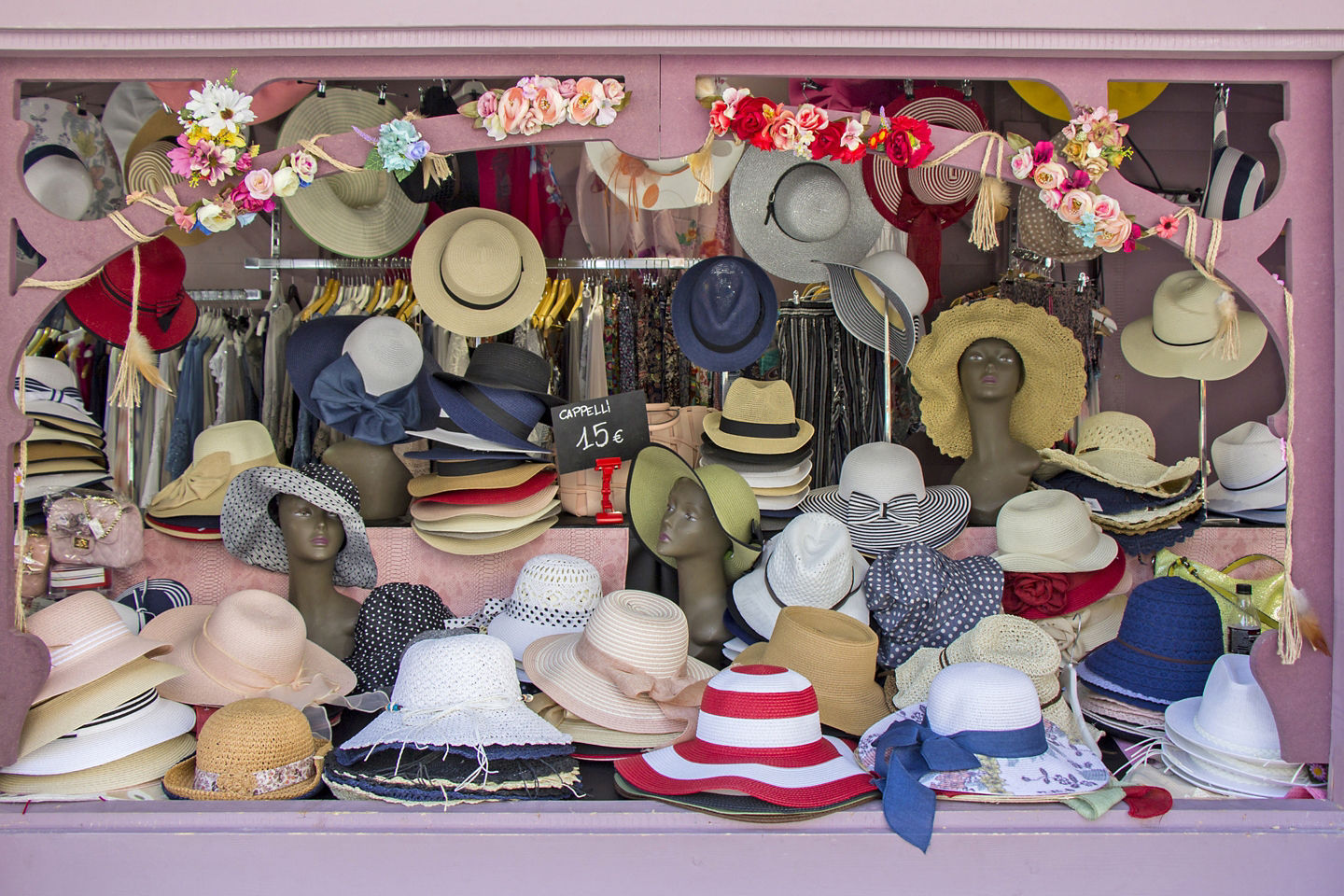 A summer market stall in Trieste displays woven straw hats in neat, colorful rows. - Trieste, Italy