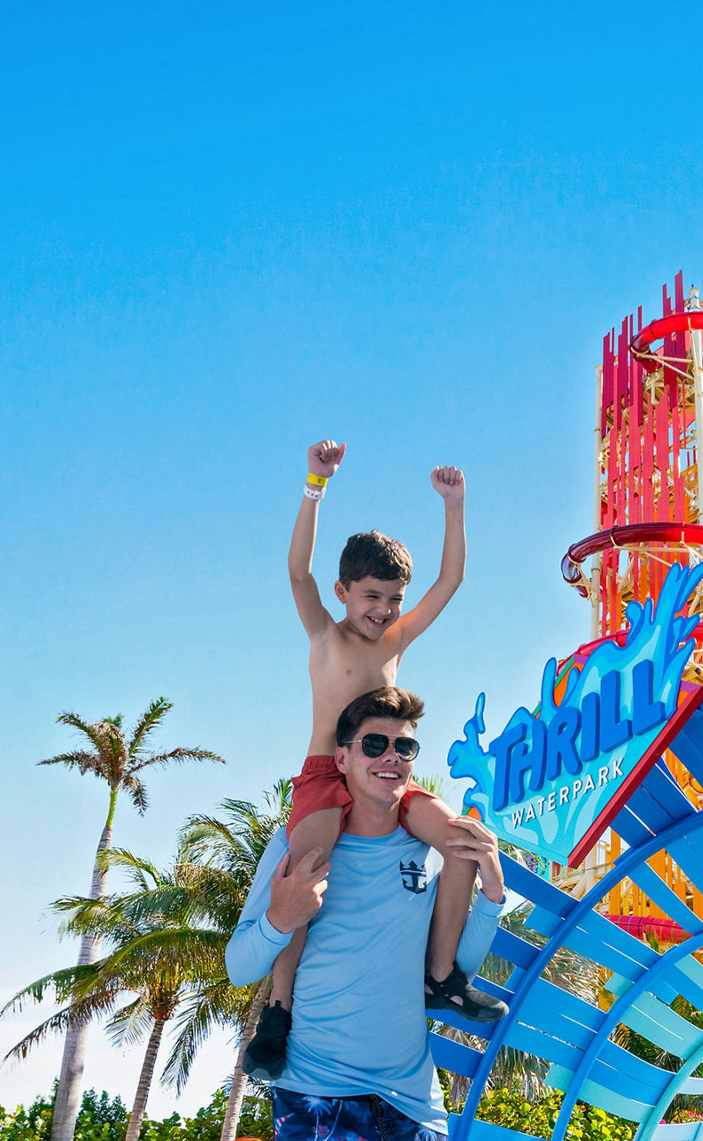 Man carrying a kid on the shoulders at thrill waterpark entrance