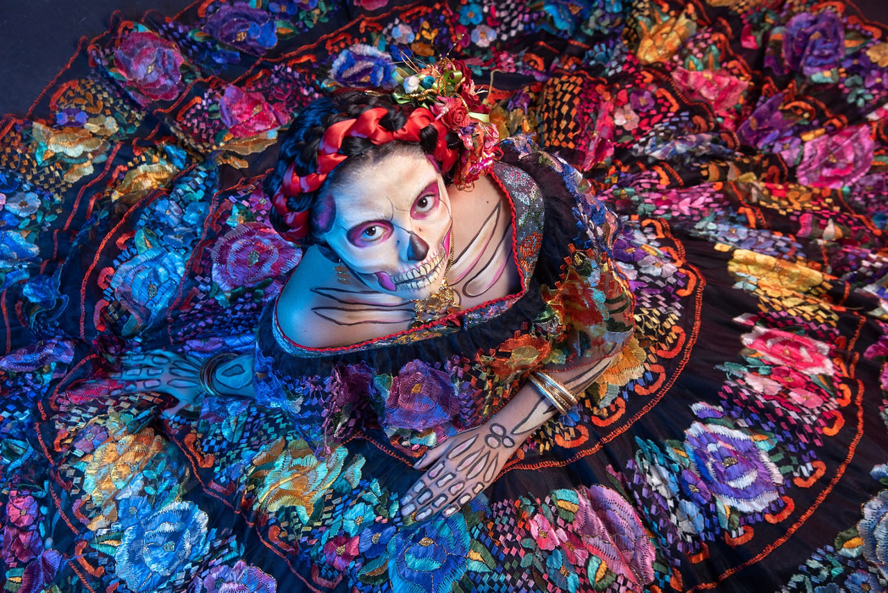 Woman dressed in a mexican chiapas, pink rebozo, and skull and bones makeup