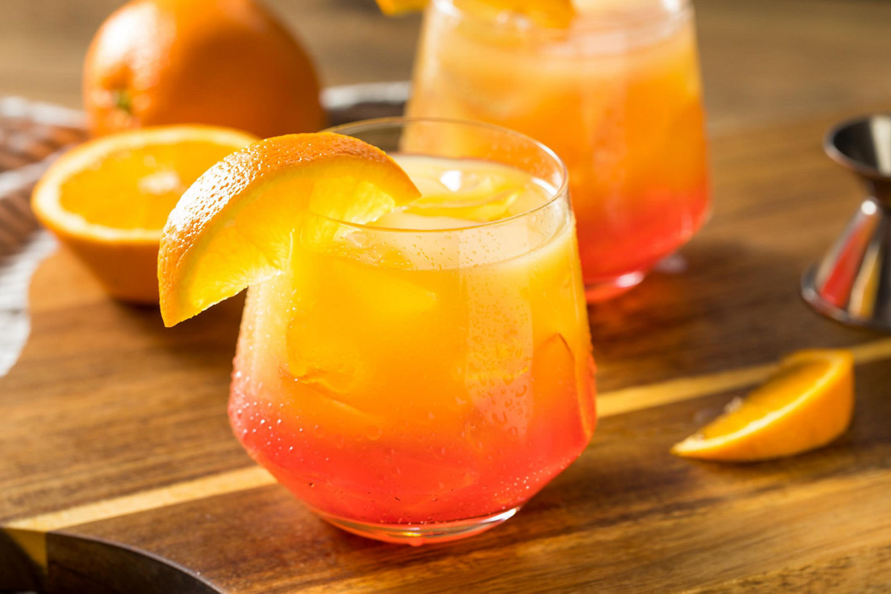 Tequila sunrise cocktail with orange slices on the side