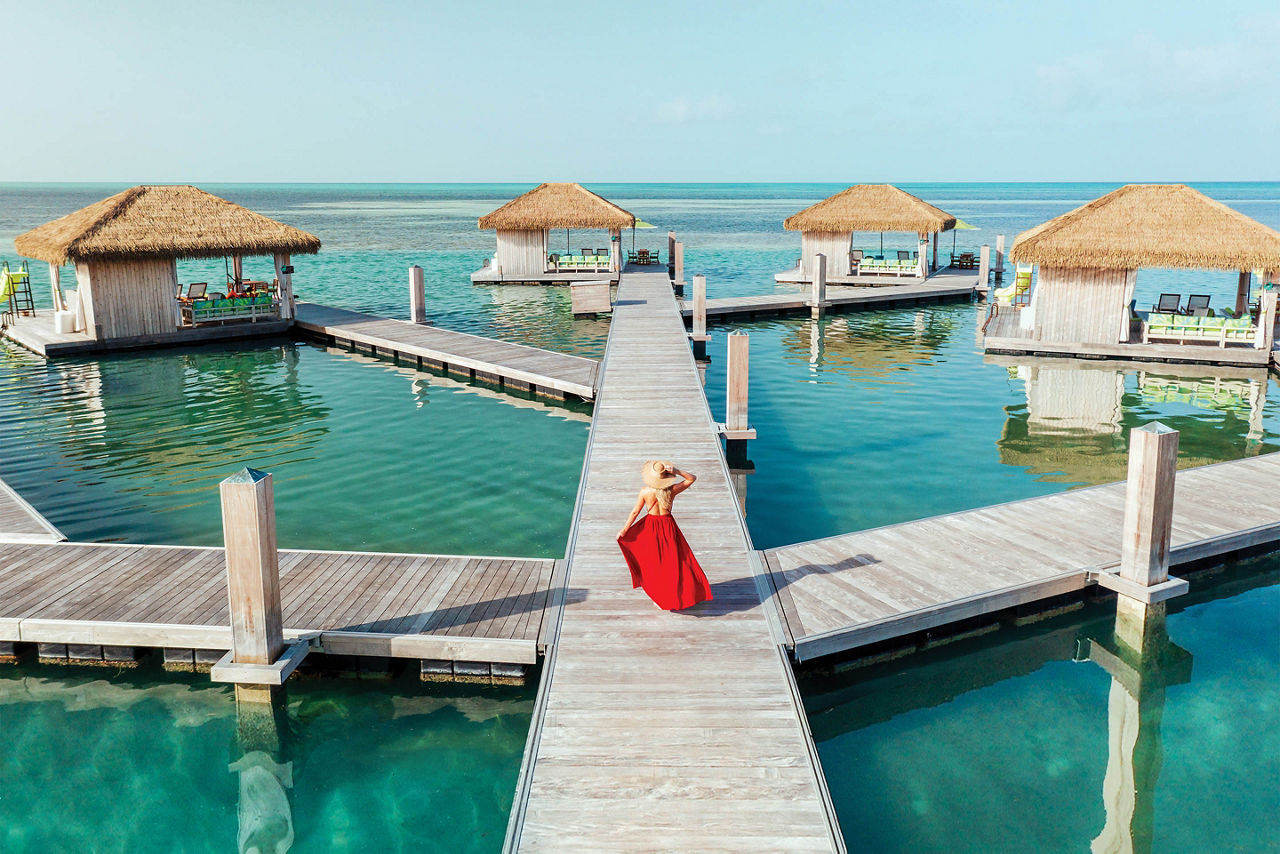 Woman in red dress walking overwater Cabanas Perfect Day CocoCay