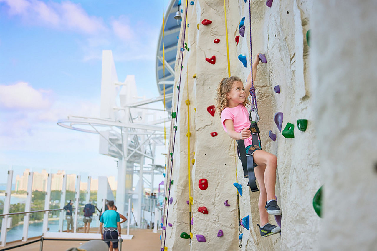 Young girl climbing on rock wall at Adrenaline Peak on Icon of the Seas