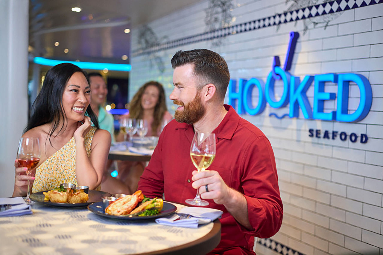 Couple enjoying dinner at Hooked Seafood at Icon of the Seas