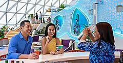 Couple sitting at Overlook Bar on Icon of the Seas while bartender makes a drink, cocktails, fun, relaxing,