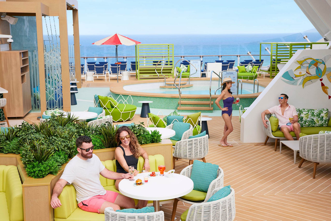 Couples enjoying lunch and drinks, snacks, on the Suite SunDeck with pool and ocean horizon in the background on Icon of the Seas
