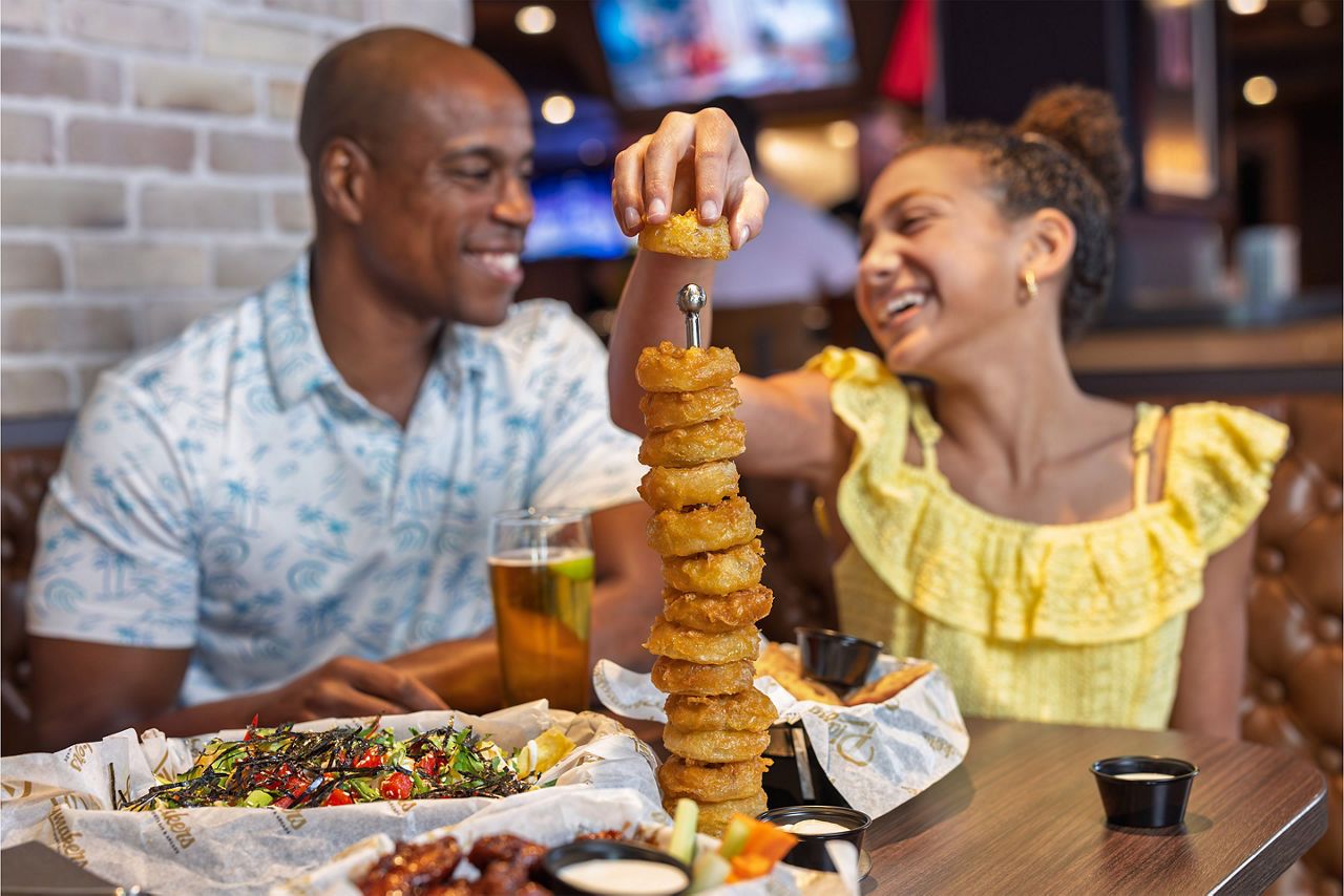 Father daughter eating at Playmakers Sports Bar and Arcade, onion rings tower