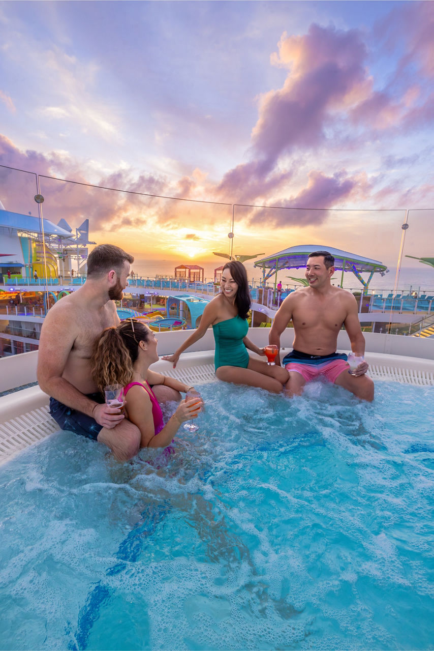 Friends in the hot tub enjoying cocktails at Chill Island during sunset