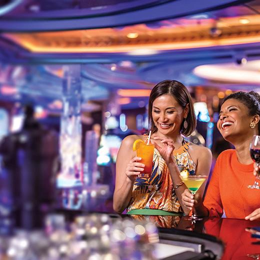 Two friends women who are enjoying drinks at casino on Royal Caribbean