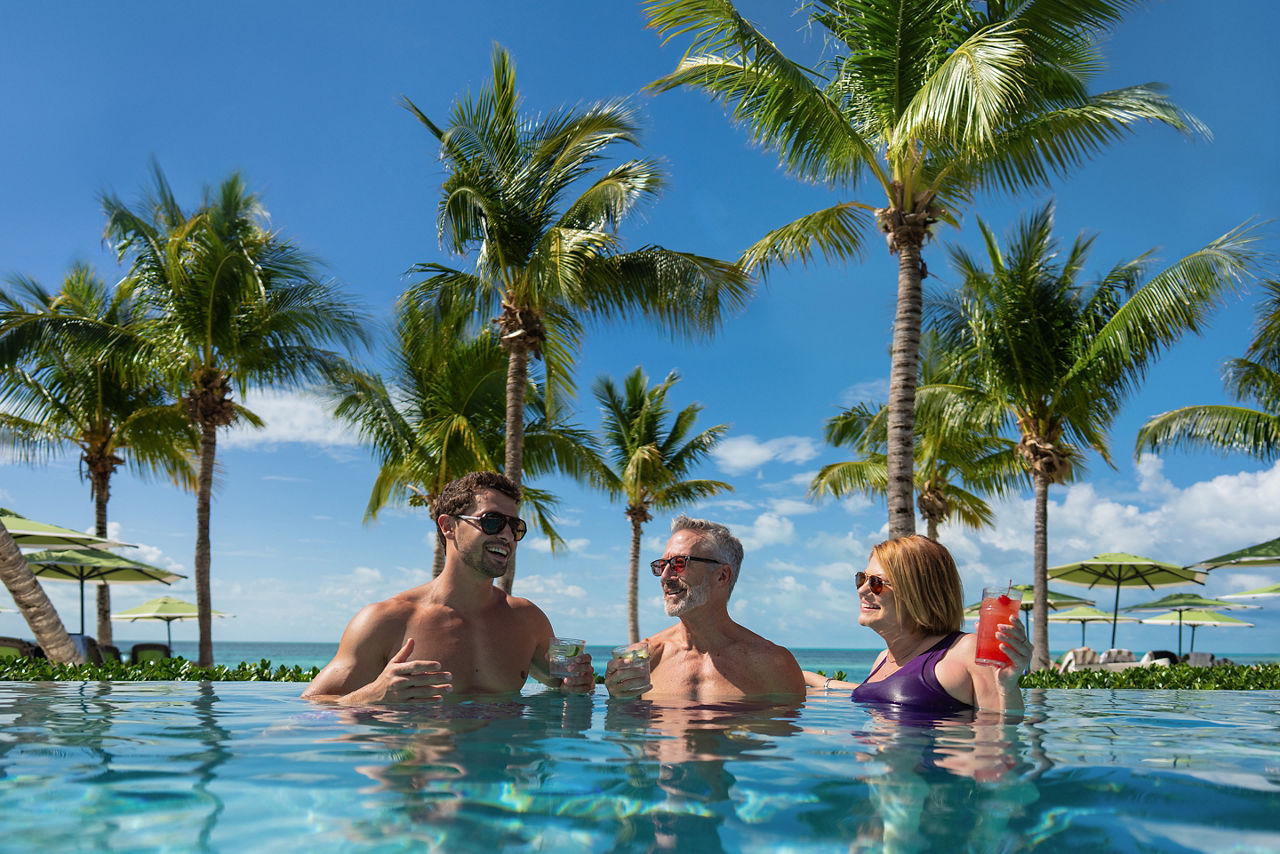 Two men and a woman conversing in the Infinity Pool, Coco Beach Club, Perfect Day at CocoCay