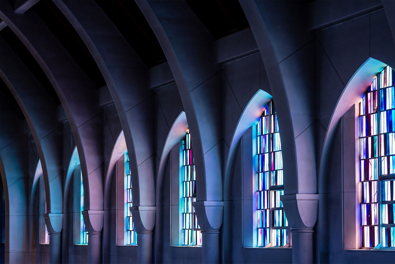 Arched columns in chapel with stained glass windows. Europe.