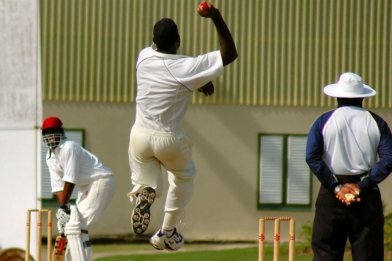 Bowler pitching in a game of cricket . The Caribbean.