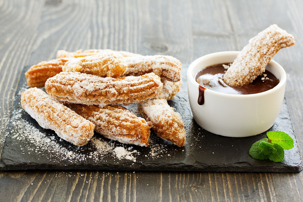 Hot chocolate surrounded by churros. 