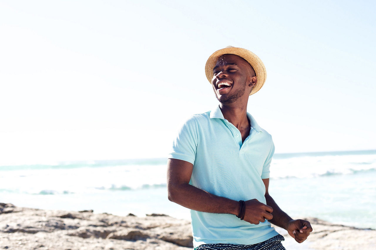 Fashionable young man smiling in a polo shirt and hat. The Caribbean.