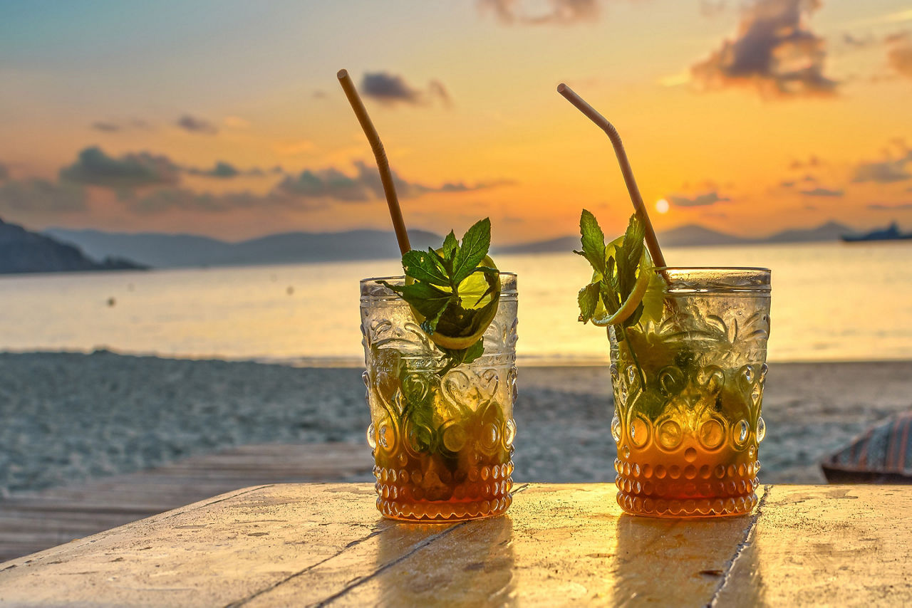 Glass of amber-gold Caribbean rum in front a sunset. The Caribbean.
