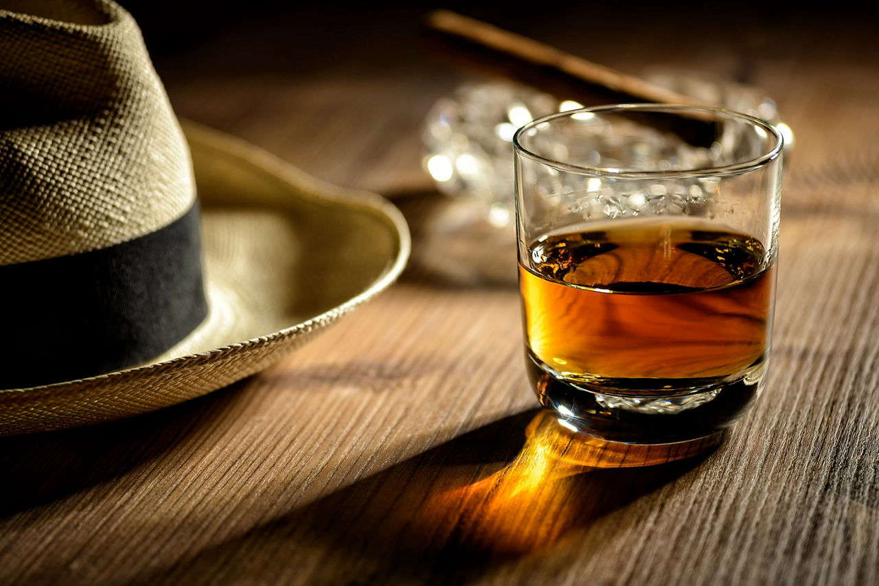 Glass of rum, cigar and a hat in a rum distillery. The Caribbean