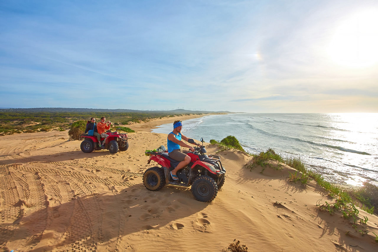 A group of friends enjoy ATV/quad biking along the oceanfront,