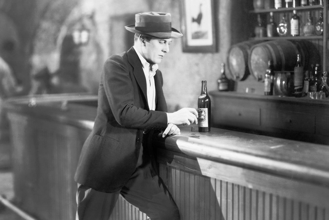 black and white photo of a man standing at a speakeasy. North America.