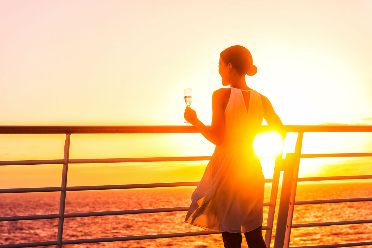 Cruise ship traveler drinking glass of champagne with the sunset.