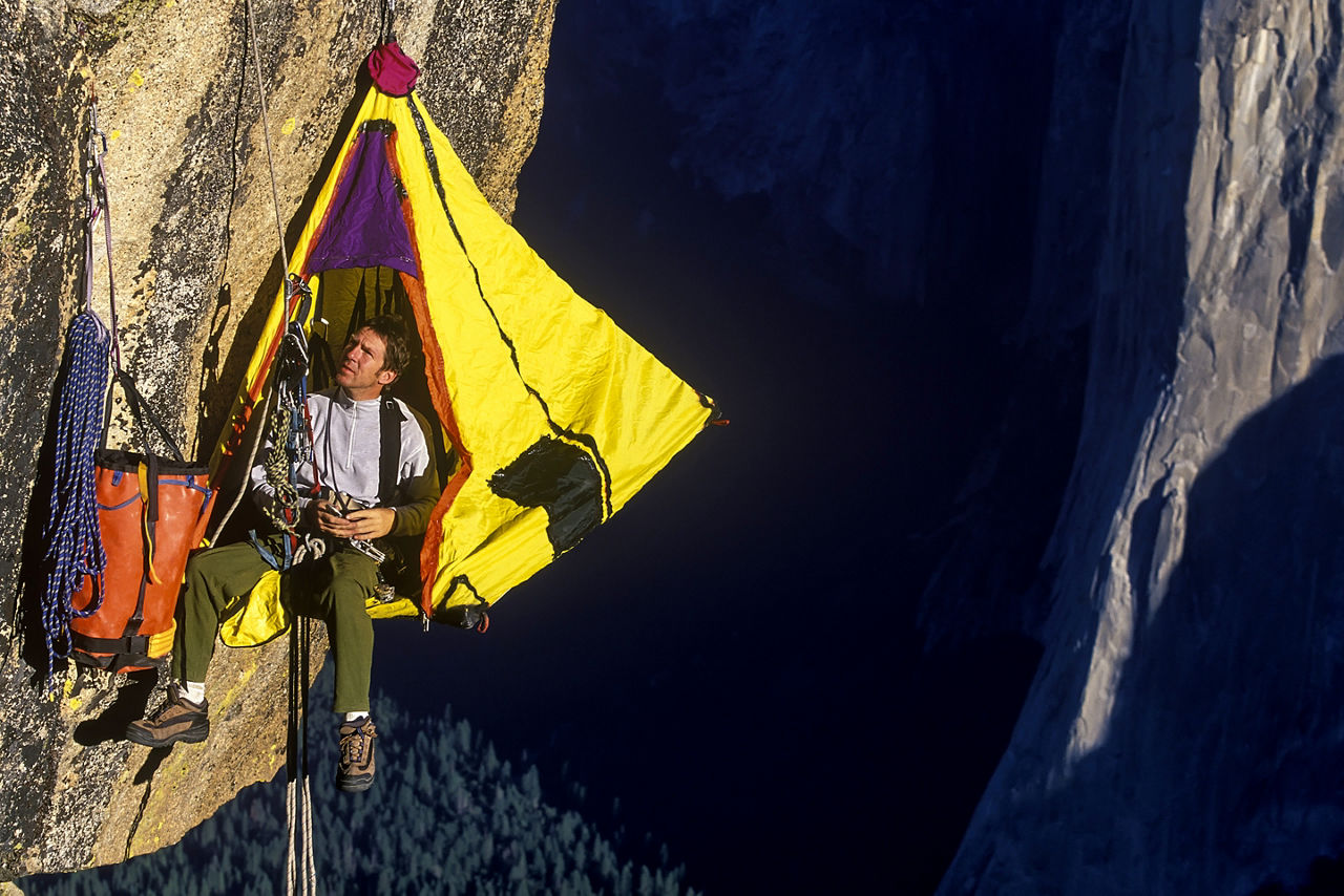 Rock climbers set up camp on the side of a mountain.