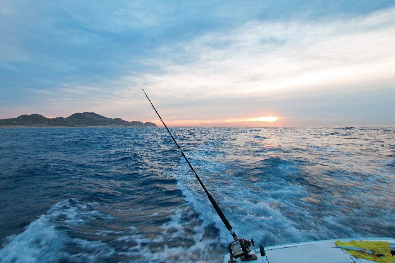 Sunrise view of fishing rod on charter fishing boat