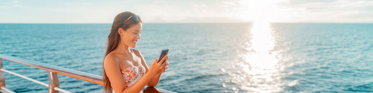 Woman on smart phone texting on ship deck.