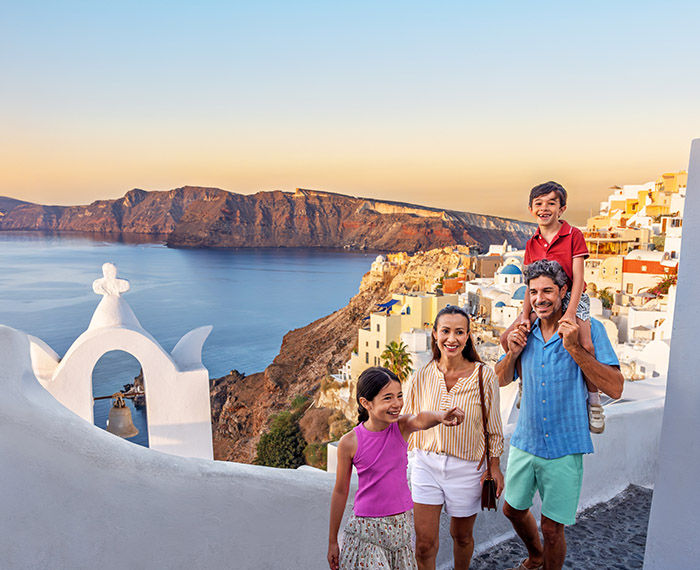 Family fun tour at Oia Village, Santorini, shoreline cliffs in background
