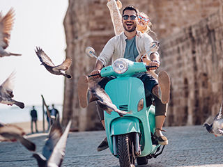 couple happily riding a scooter with birds flying around