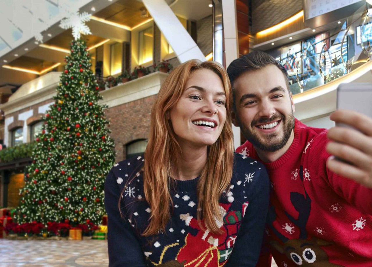 Couple Taking a Selfie with a Christmas Tree in the Background as part of the Holiday Cruise Experience