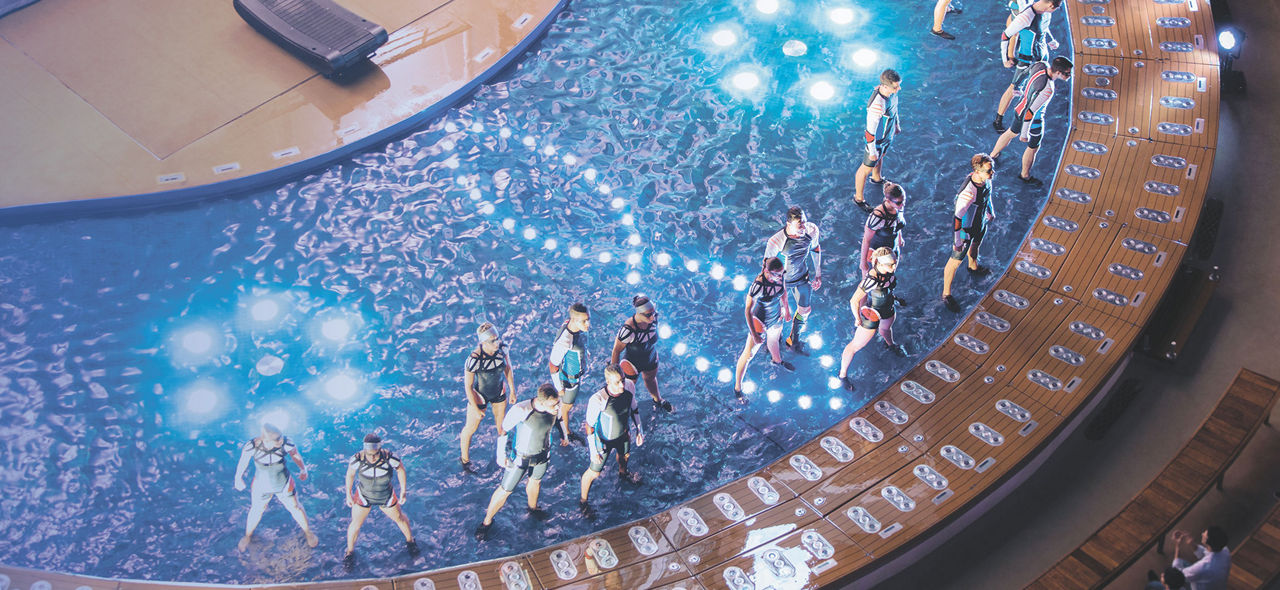 An aerial view of a group of performers over water during an Aqua Theater cruise show.