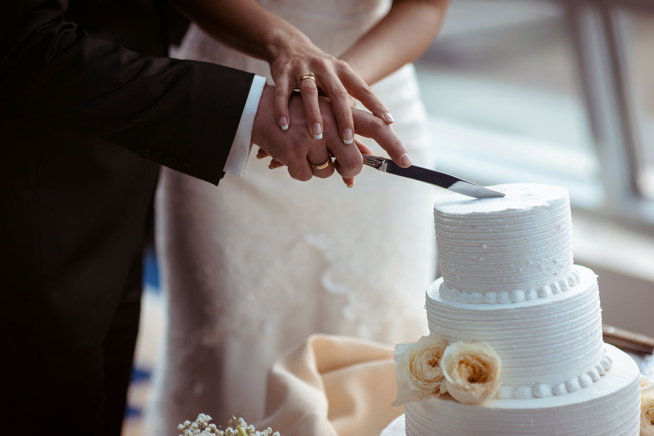 A bride and a groom is cutting their wedding cake. beautiful cake. nicel light. wedding concept