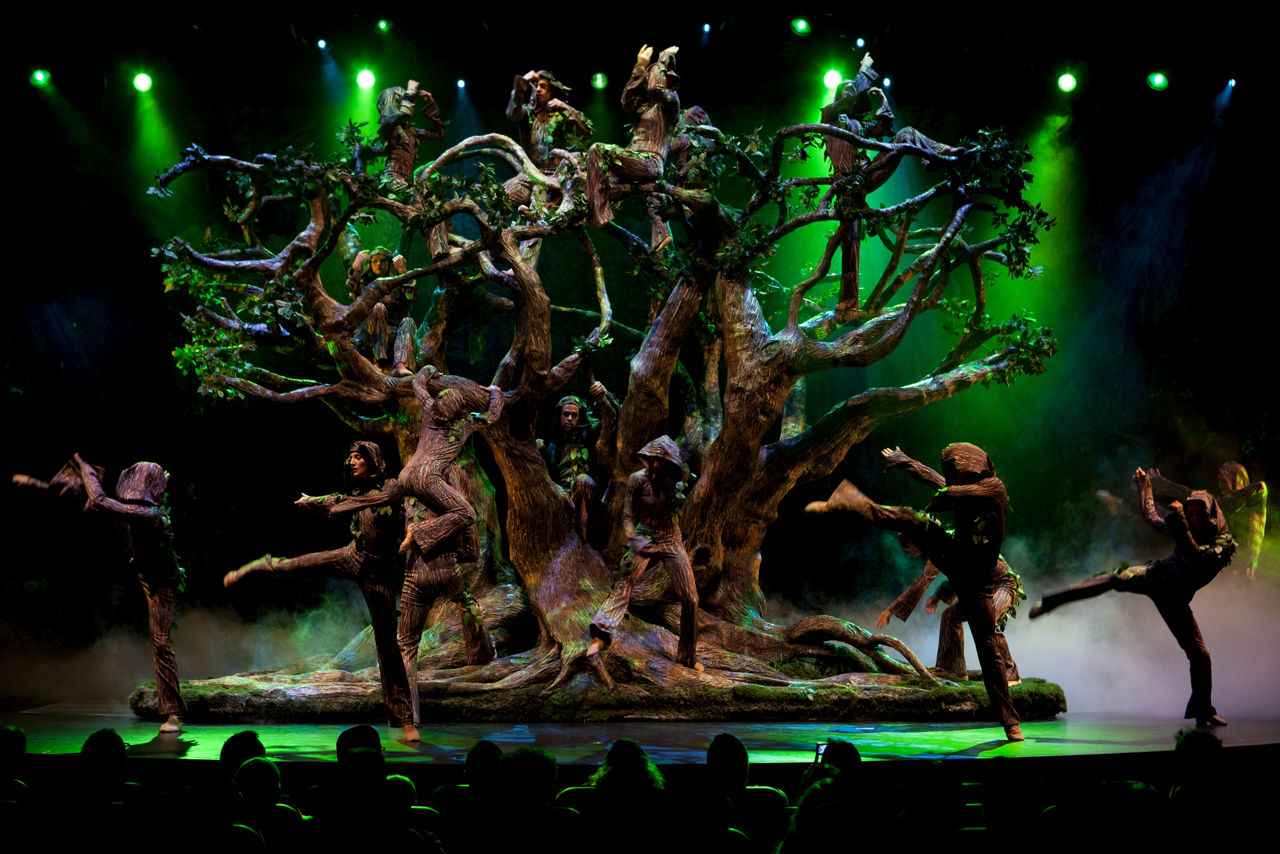 Performers forming a tree on stage with green lights during the Blue Planet Cruise Show on Allure of the Seas