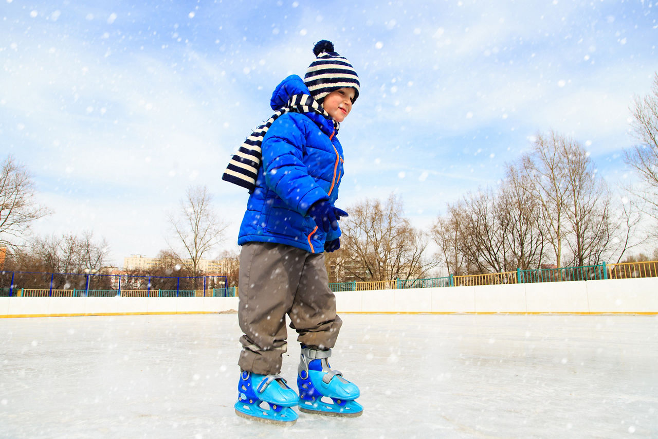 cute little boy learning to skate in winter snow