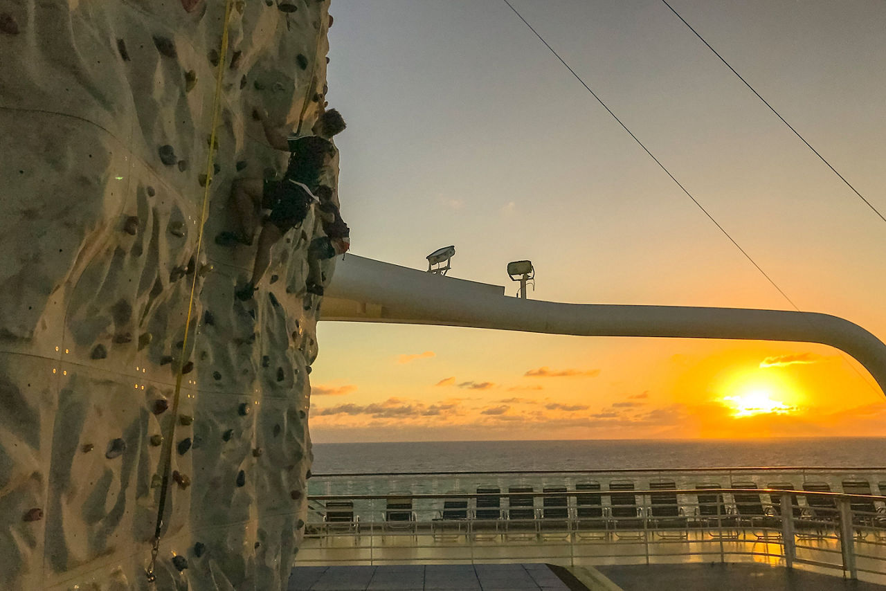 Man Climbing The Rock Wall During Sunset