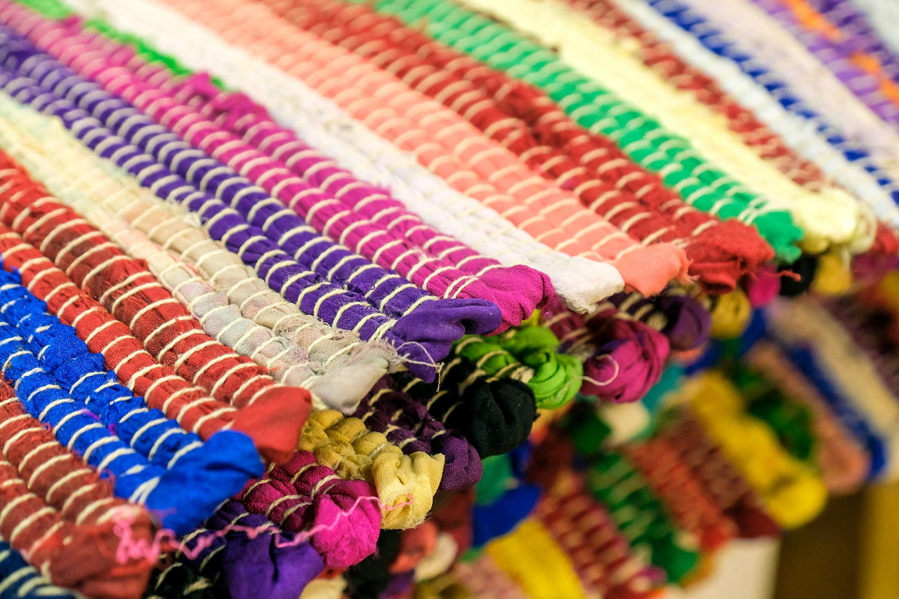 An assortment colorful rugs piled up at a market