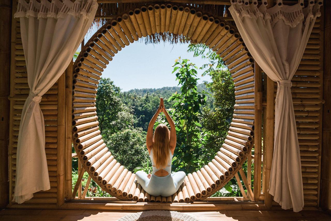 young girl does yoga outside in bamboo house. Bali, Indonesia