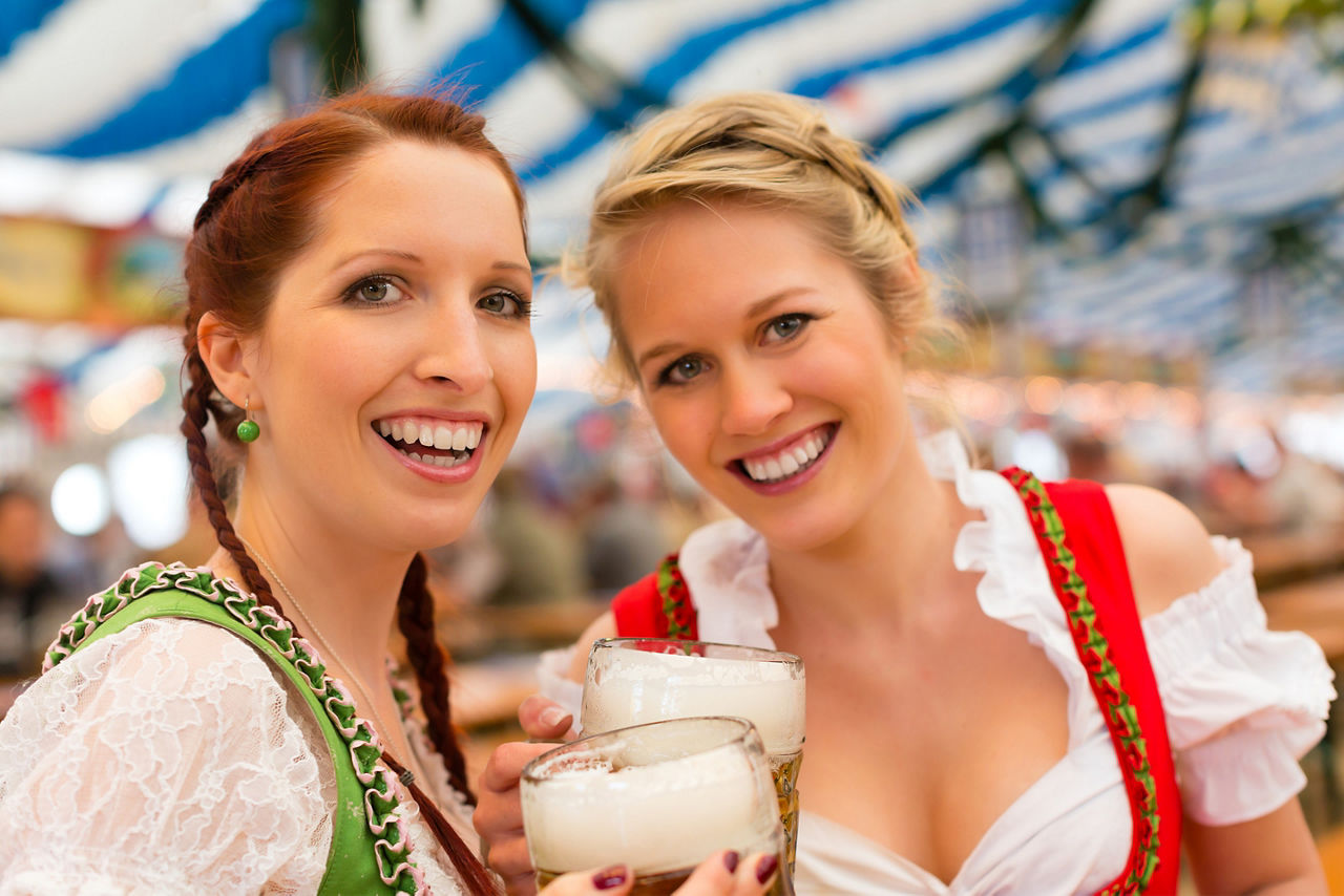 Young women in traditional Bavarian clothes - dirndl or tracht - on a festival or Oktoberfest in a beer tent