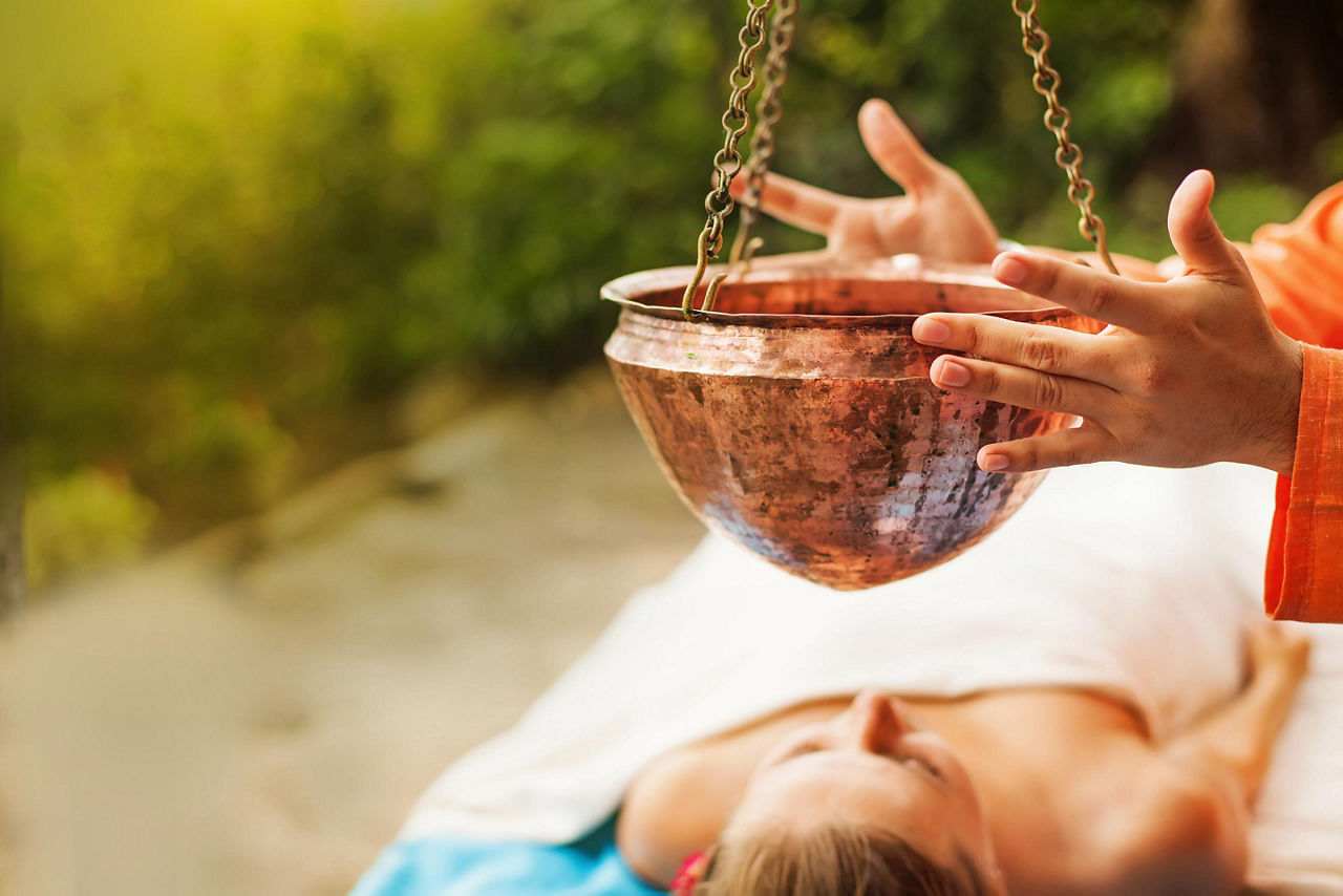 Woman getting ayurvedic treatment Shirodara with hot oil pouring on a forehead