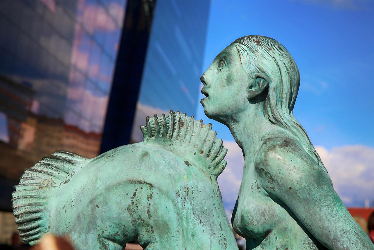 Little Mermaid statue sitting on a rock on the harborfront in the northern Kastellet area in Copenhagen, Denmark