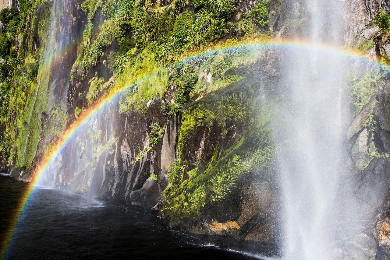 A rainbow shining over a waterfall in New Zealand