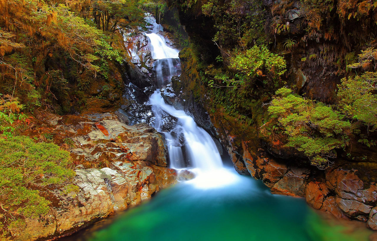 Falls Creek with a waterfall flowing over the mountain in the National Fiordland Park, New Zealand