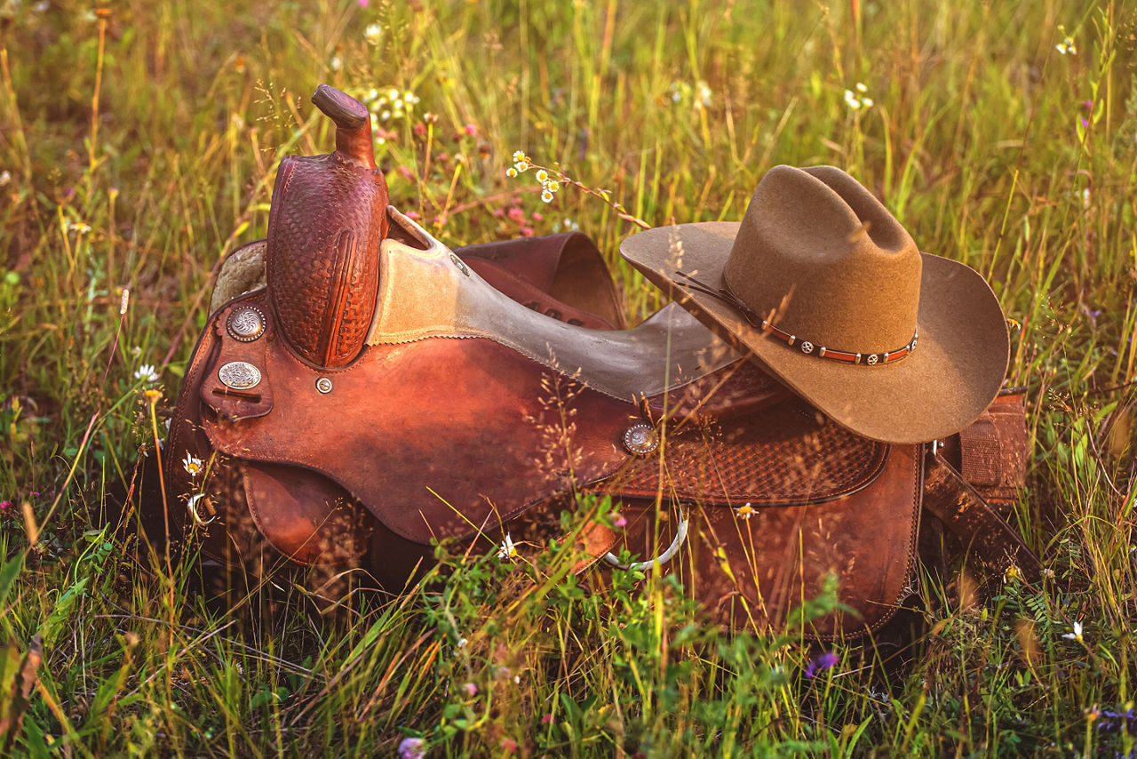 Texas rancher’s cowboy hat and boots laid on green grass. Galveston.