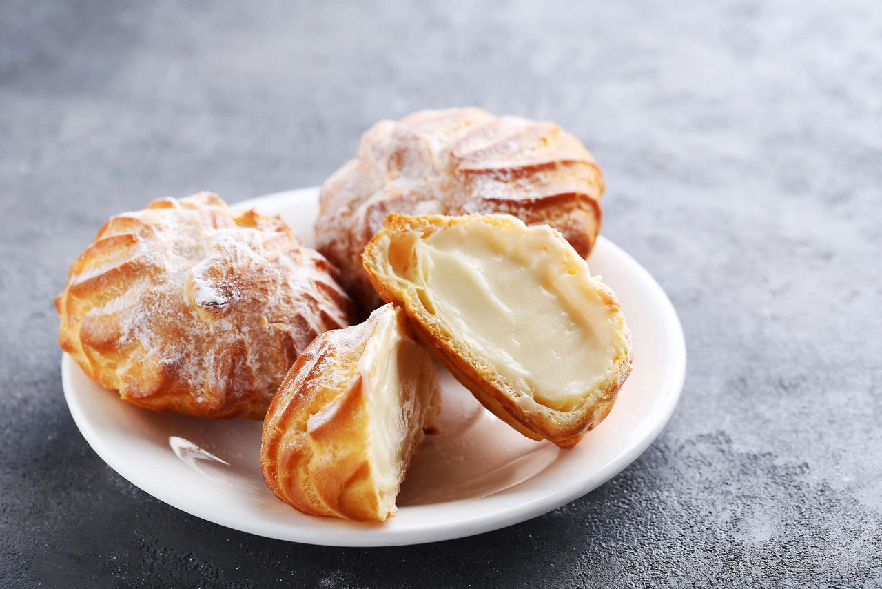 Four profiteroles cream pastries on a white plate