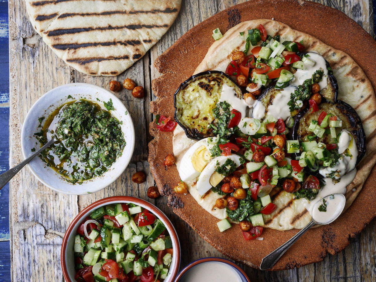 A warm toasted pita bread topped with eggplant, tzaziki sauce, and israeli salad