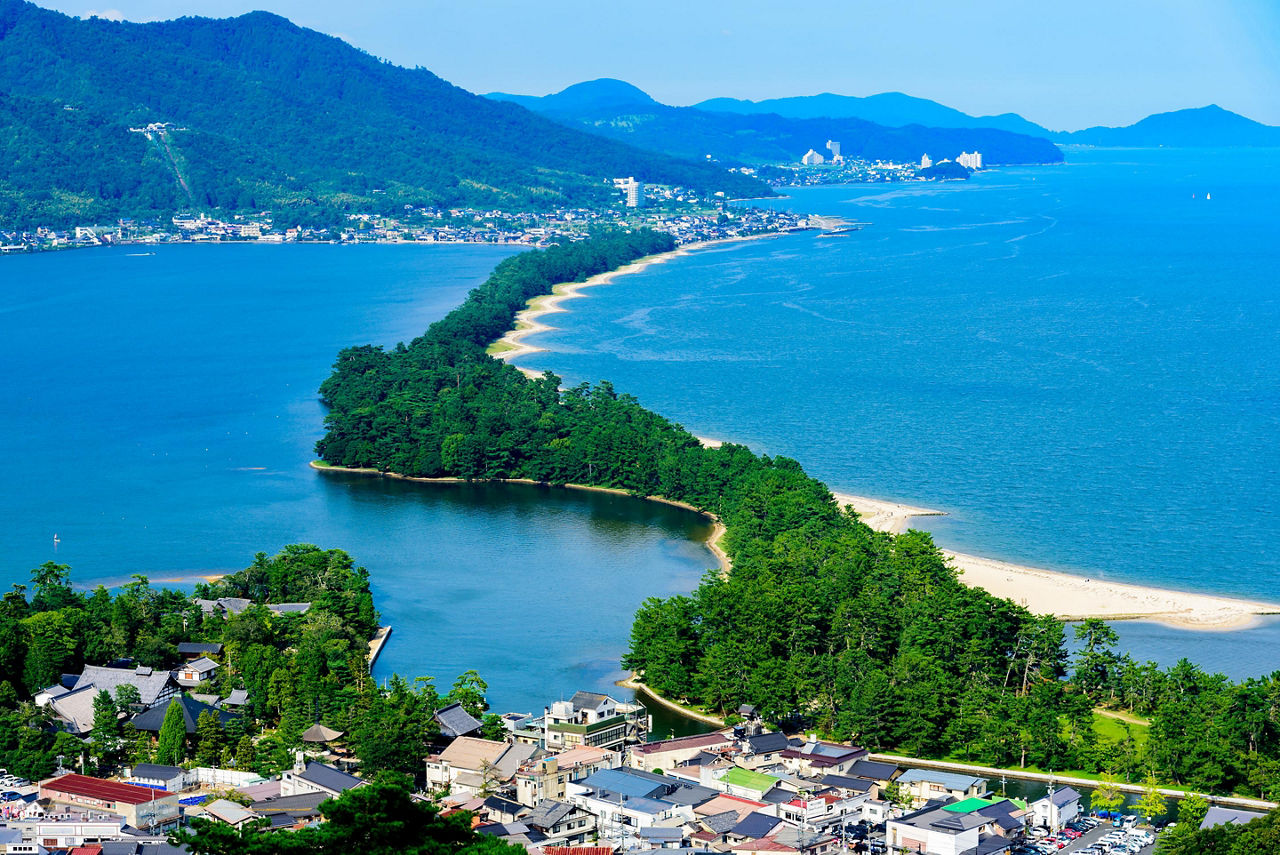 A bridge crossing the beach with temples on either side filled with trees