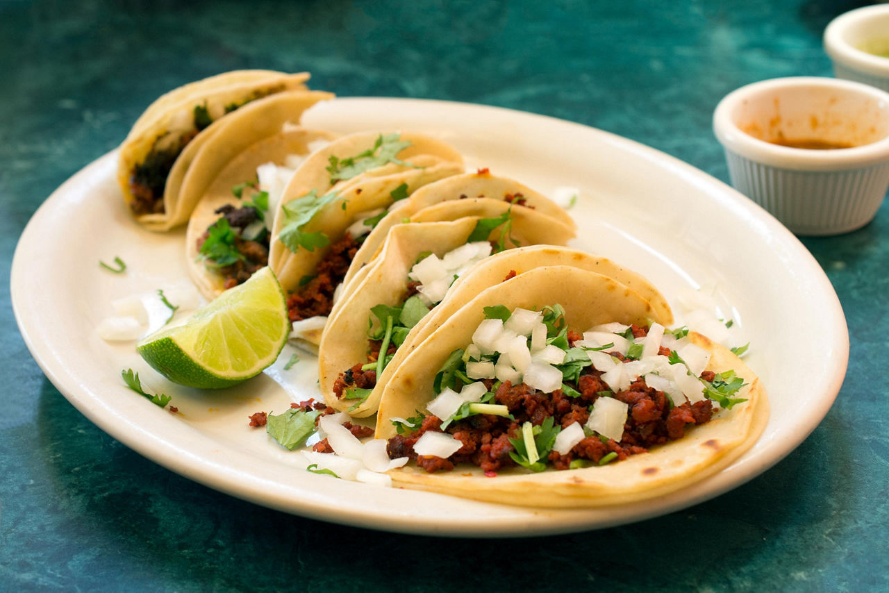 Chorizo tacos on a white plate with a sliced lime