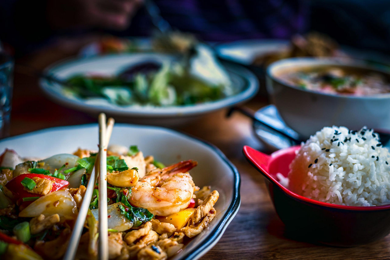 Colorful thai food in bowls with shrimp pad thai and bowls of rice