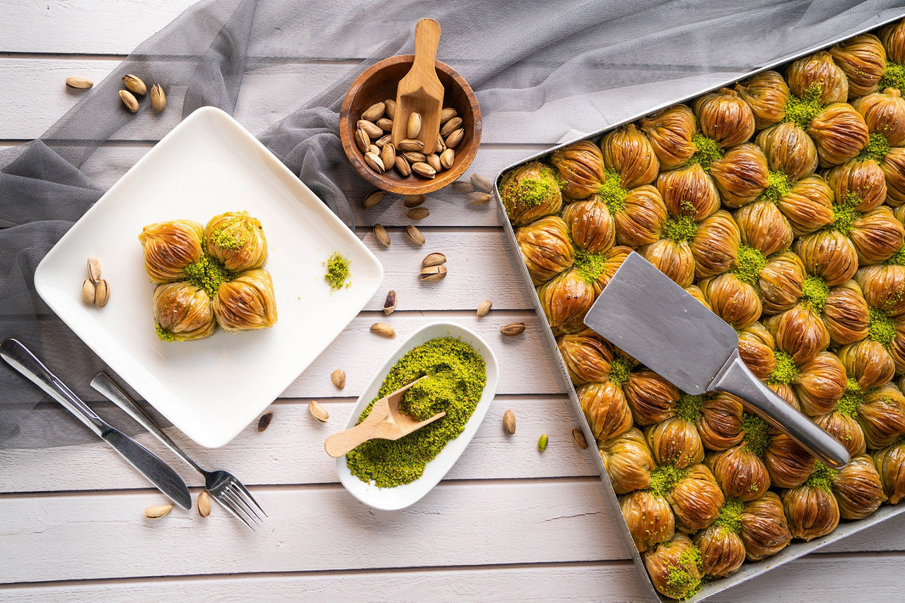 Turkish desert baklava with peanut,  pistachio, hand on fork and Turkish tea 