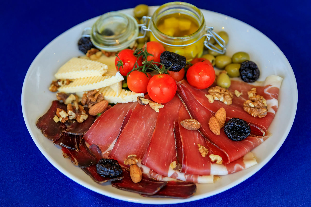 Antipasto plate of Njeguski prsut cured meat, cheese, olive oil, fresh tomatoes and nuts.