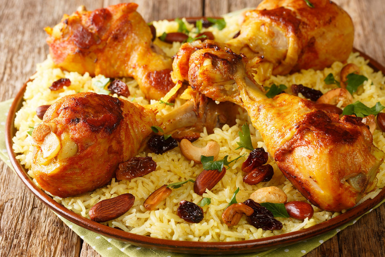 Homemade Arabic spiced rice and chicken topped with nuts, raisins closeup in the plate on the table. 